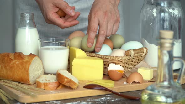 Farmer Hands Taking Eggs From Basket on Background of Rustic Products Milk Bread Butter