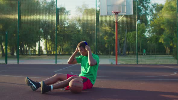 Streetball Player Listening Music on Outdoor Court alt