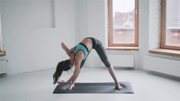 Young Sporty Brunette Girl in Sportswear Does Exercises in Bright Room at Home