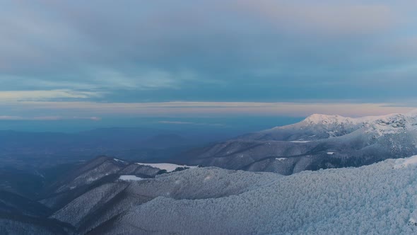 Dark eve sky with light clouds over snow covered mountain peaks alt