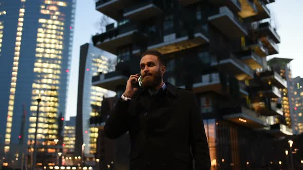 Young handsome caucasian bearded businessman talking smartphone alt