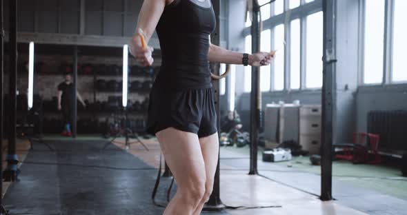 Closeup Young Beautiful Blonde Woman Exercising with Jump Rope Working Out in Large Atmospheric Gym alt