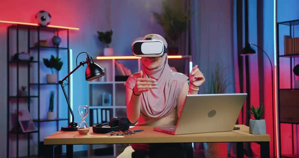 Muslim Woman in Headscarf Working on Imaginary Screen Using Augmented Reality Goggles alt