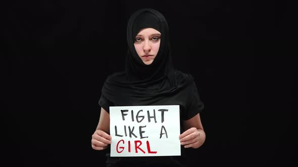 Muslim Woman in Hijab Posing with Fight Like a Girl Sign at Black Background alt