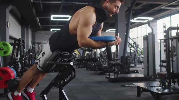 Man Athletic Build Trains Muscles of Abs in Gym Lifting Weight Plates Side View alt