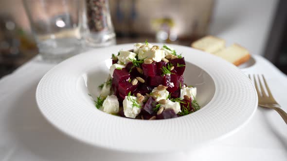 Salad with beetroot, feta cheese and sunflower seeds in white plate, rotates alt