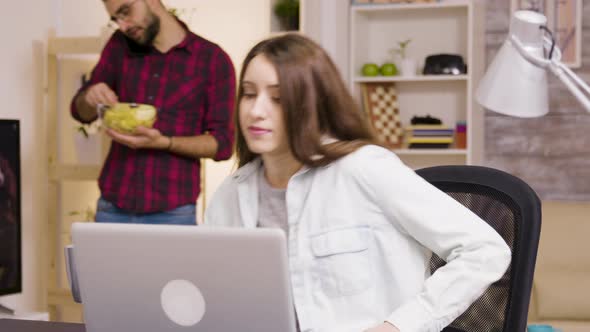 Girl Enjoying a Cup of Coffee While Working on Laptop in Living Room alt