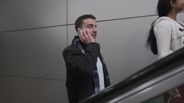 Businessman on escalator talking on cell phone