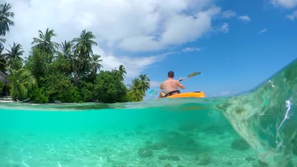 Water shot of a man kayaking around a tropical island. alt