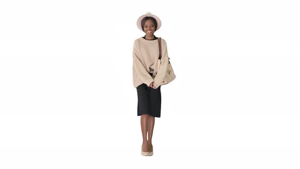 Smiling African American Woman in Knitwear and White Hat Posing While Walking on White Background alt
