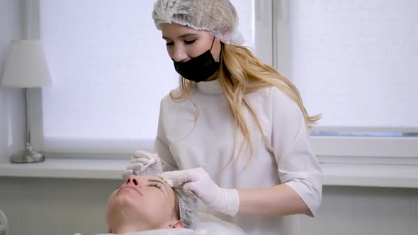 Doctor Beautician Removes White Cream From the Face of His Patient Lying alt