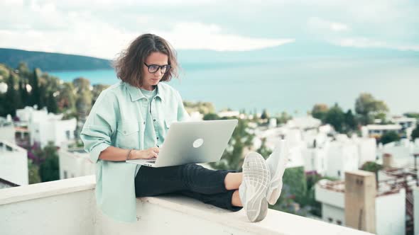Young Woman Freelancer Working with Her Laptop on the Roof Terrace. alt