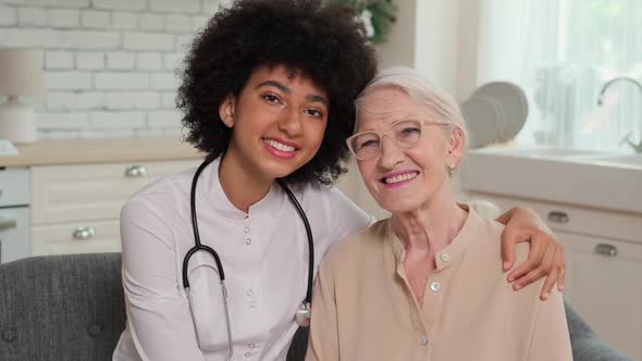 Afro American Woman Doctor and Patient Senior Woman Sitting on Sofa and Smiling alt