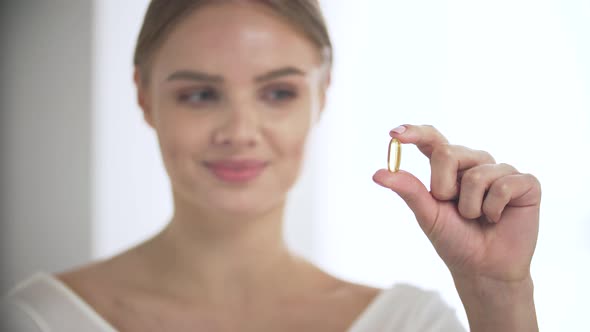 Health Supplement, Smiling Woman With Omega Pill In Hand alt