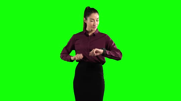 a Caucasian woman in suit checking her smarwatch in a green background