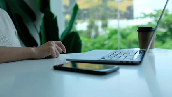 woman tapping fingers while working on laptop computer with mobile phone