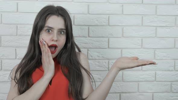 The surprised beautiful girl offers goods. alt