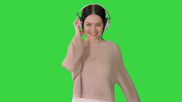 Smiling Female with Headphones Walking and Dancing To the Music on a Green Screen, Chroma Key. alt