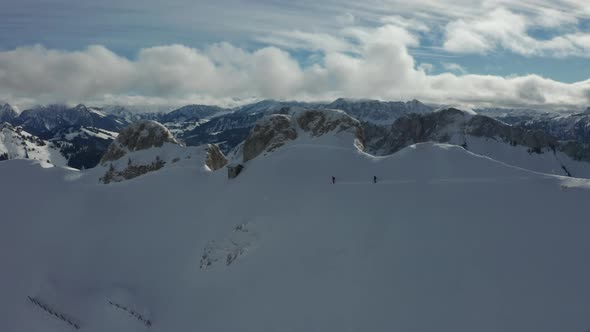 Aerial of two skiers on snow covered slope with a beautiful mountainscape in the background alt