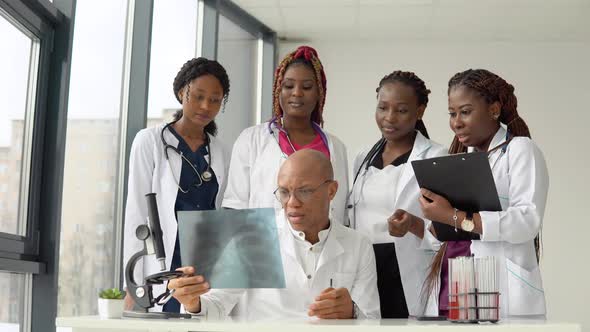 Five African American Doctors Man and Women Examine an Xray While Standing at a Table alt