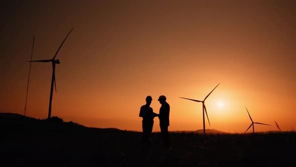 Silhouette Engineer and Inspector Working Together on Windmill Farm alt