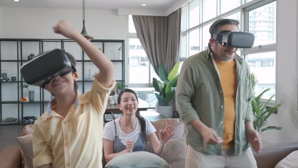 Asian father and son playing a game fighter using VR Headsets.