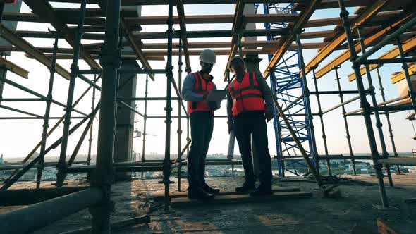 Men in Uniform Discuss Construction on a Site alt