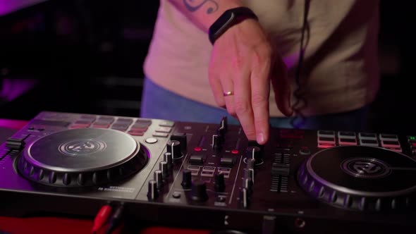 Close up DJ using controller console to mix music list in club. Caucasian deejay person alt
