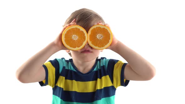 Little Boy Posing in Studio on a White Background with Cut Orange Instead of Eyes