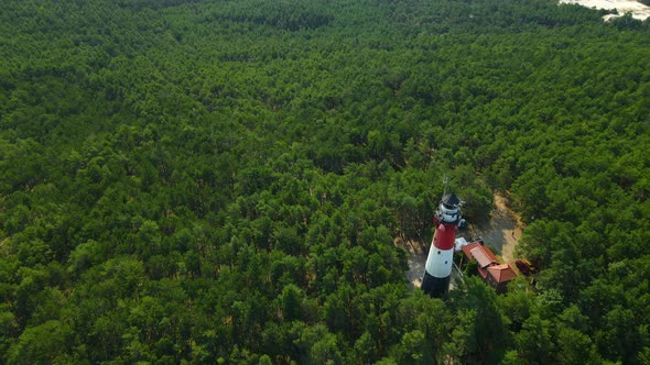 Incredible White and red light House stands tall above trees in a dense forest as a drone circle orb alt