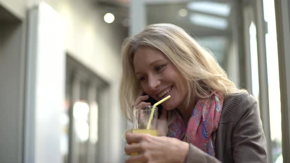 Woman talking smart phone while holding a juice glass