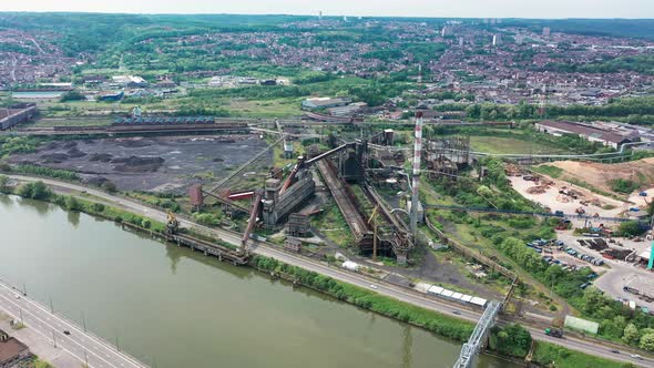 Aerial view of abandoned steel factory with urban background. Next to river and highway with cars dr alt