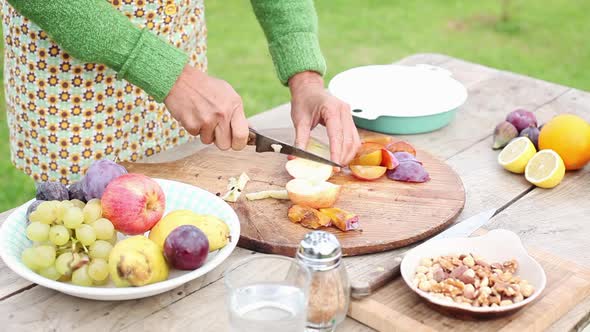 Woman cutting fruits outdoors alt