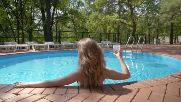 Young Relaxed Woman Is Enjoying Good Summer Weather Lying in Swimming Pool of Hotel