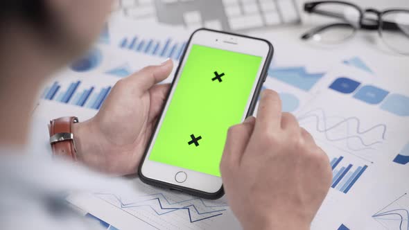 Businesswoman working and looking at green screen on smartphone