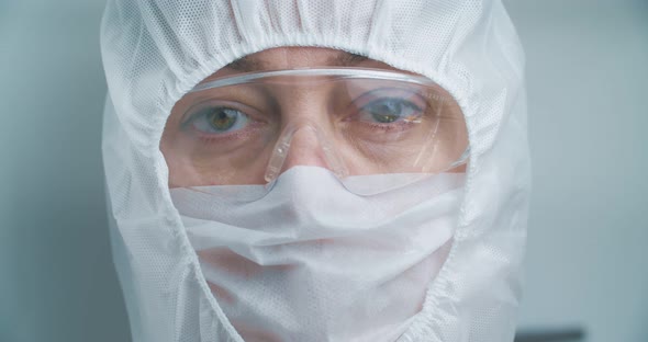 A doctor in protective clothing, a mask and goggles, close-up. Tired look. Antivirus suit