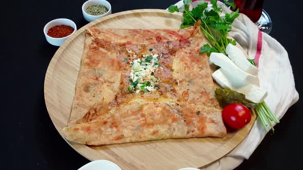 Delicious crepe with cheese served with appetizers and tea on a wooden board