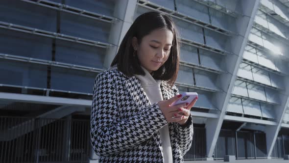 Young Adult Woman Typing on Her Smartphone in the City Downtown alt