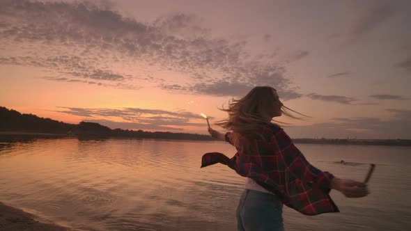 Beautiful Woman Smiling in Summer with Sparklers Dancing Spinning in Slow Motion on the Beach at alt