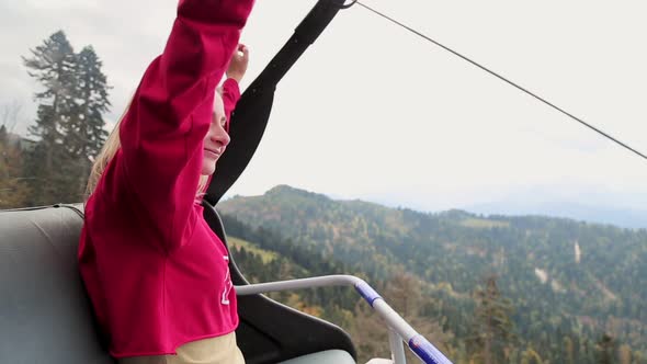 A Young Female Tourist Admires the View of the Mountains While Sitting Inside a Modern Cable Car alt