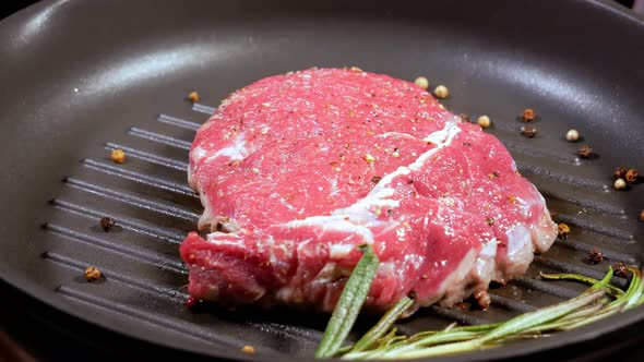 The Meat Steak Is Fried with a Leaf of Rosemary and Peppercorns in a Slowly Rotating Pan