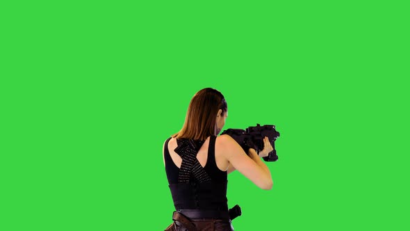Cyberpunk Girl in Black Military Clothes Walks with Machine Gun Taking an Aim on a Green Screen