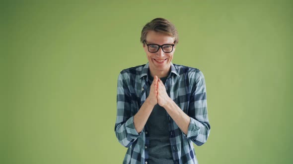 Portrait of Sly Young Man Rubbing His Hands and Smiling Looking at Camera alt