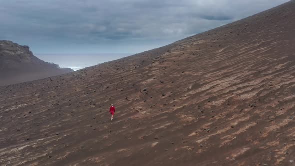 Tourist in Red Sweatshirt Walks Across the Volcanic Hill alt