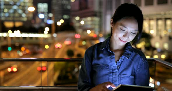 Woman looking at tablet computer at night