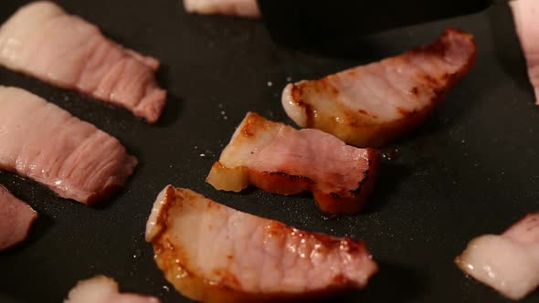 Frying smoked bacon on frying in pan alt