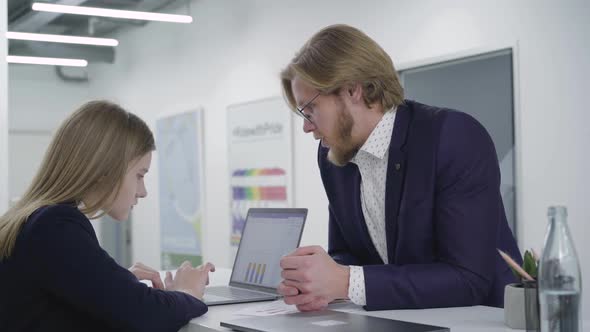 Young Bearded Man Trying To Cheer Up Female Colleague, Who Involved in Work on Netbook. Woman Does alt