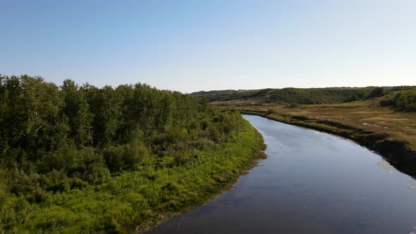 Fly over Battle River near Wainwright, Alberta. Aerial 4K Drone footage of pull back through arc of alt