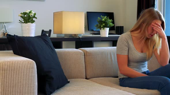 Young Woman Sits on a Couch in a Living Room and Woman Is Angry - Watch TV alt