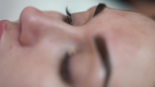 Closeup Eye of Young Slim Woman in Beauty Salon Doing Permanent Eyebrow Tattooing alt